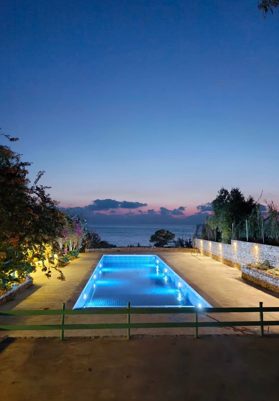 Side B pool illuminated at dusk with sea view